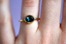 Lade das Bild in den Galerie-Viewer, Ring aus 750er/18k fairem Gelbgold mit einem blau-grünen ovalen Turmalin in einer Zargenfassung. Ring am Finger.