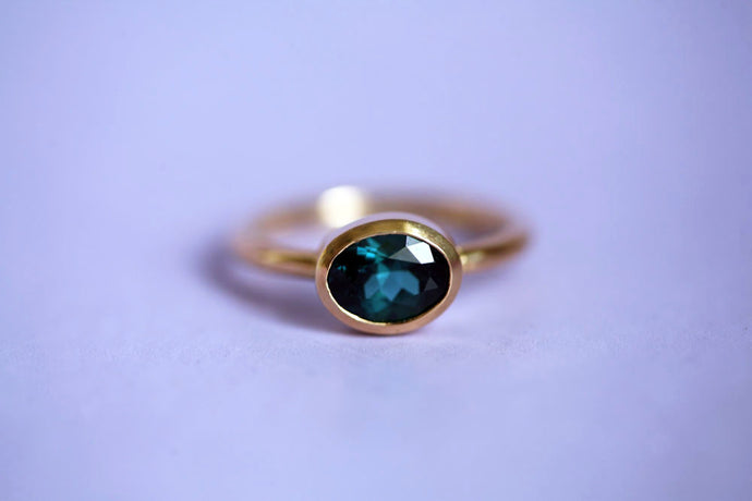 Ring aus 750er/18k fairem Gelbgold mit einem blau-grünen ovalen Turmalin in einer Zargenfassung. Ansicht Ring von vorne.